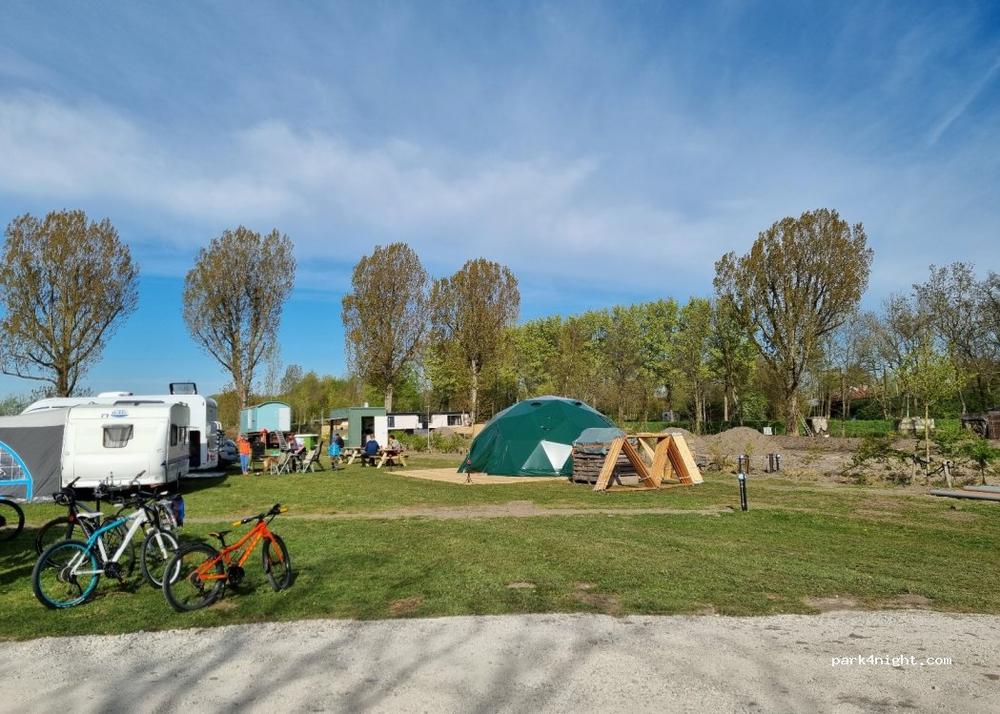 Une image montrant un camping avec des tentes, des caravanes et des arbres.