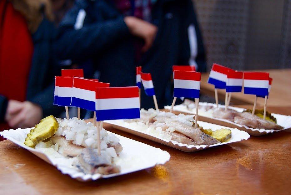 Plusieurs assiettes de harengs surmontées de petits drapeaux néerlandais.