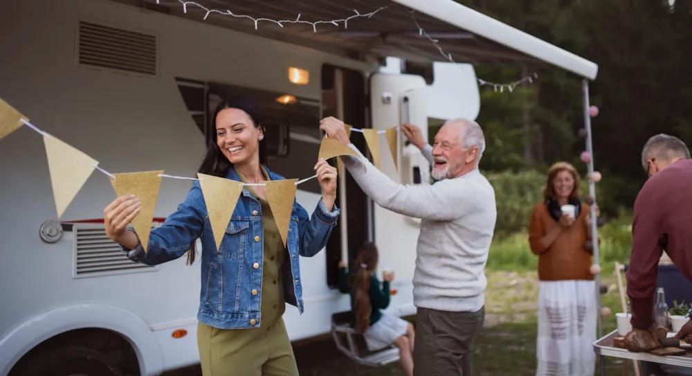Une famille est en train de décorer un camping-car avec des fanions.