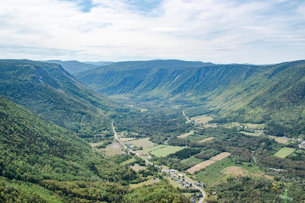 Une vue aérienne de montagnes et de vallées verdoyantes avec une route qui serpente à travers.