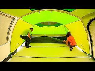 Un homme et une femme installent une tente verte et jaune.