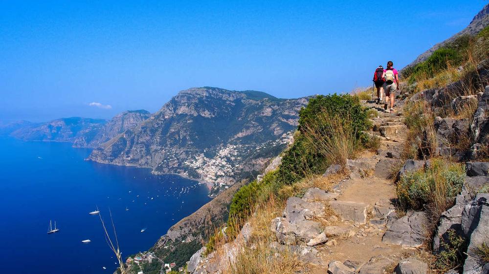 Une randonnée sur un sentier rocheux avec une vue imprenable sur la mer Méditerranée et les montagnes en arrière-plan.