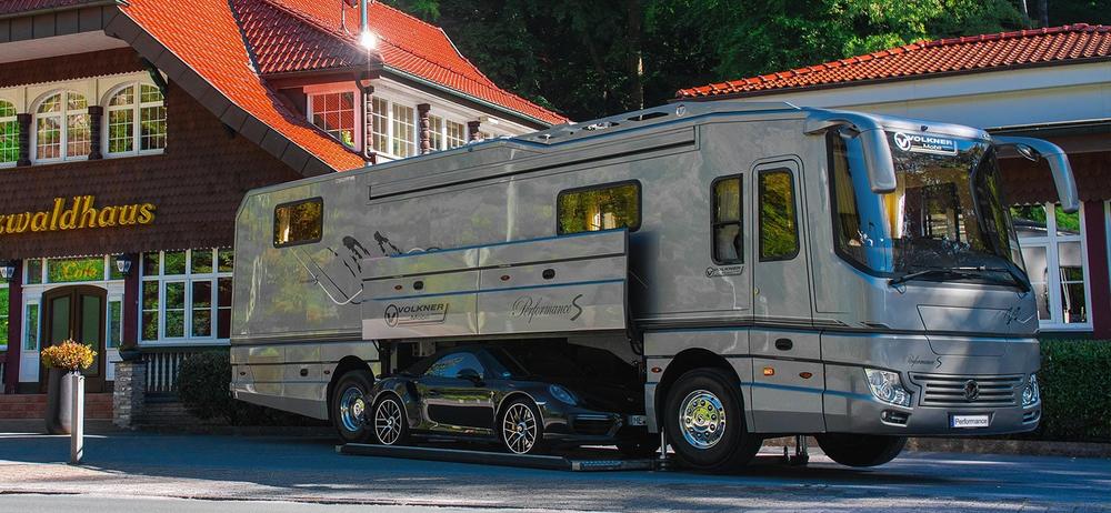 Un camping-car de luxe avec une Porsche à lintérieur.