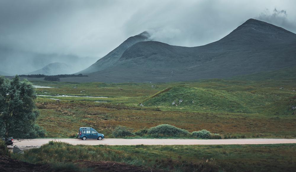 Une camionnette bleue est garée sur une route étroite dans les Highlands écossais.