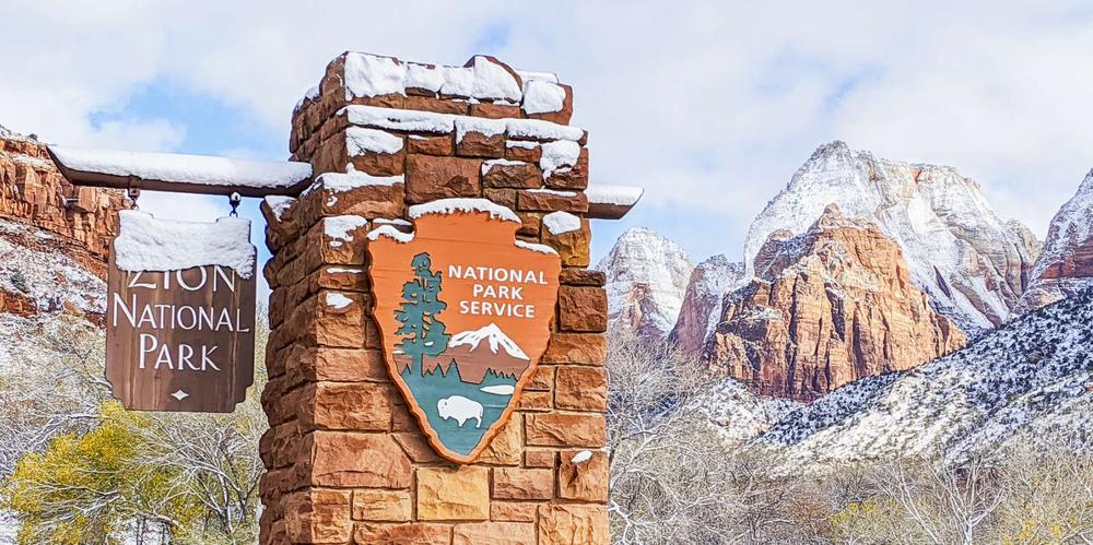 Le panneau du parc national de Zion se trouve devant des montagnes enneigées.