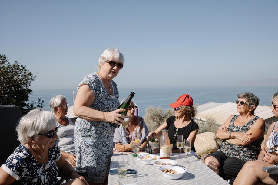 Un groupe de femmes âgées assises autour dune table en train de trinquer.