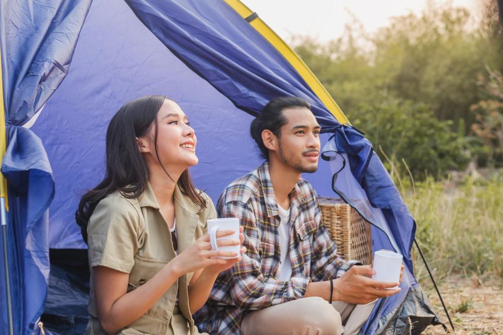 Un jeune couple est assis dans une tente et boit du café.