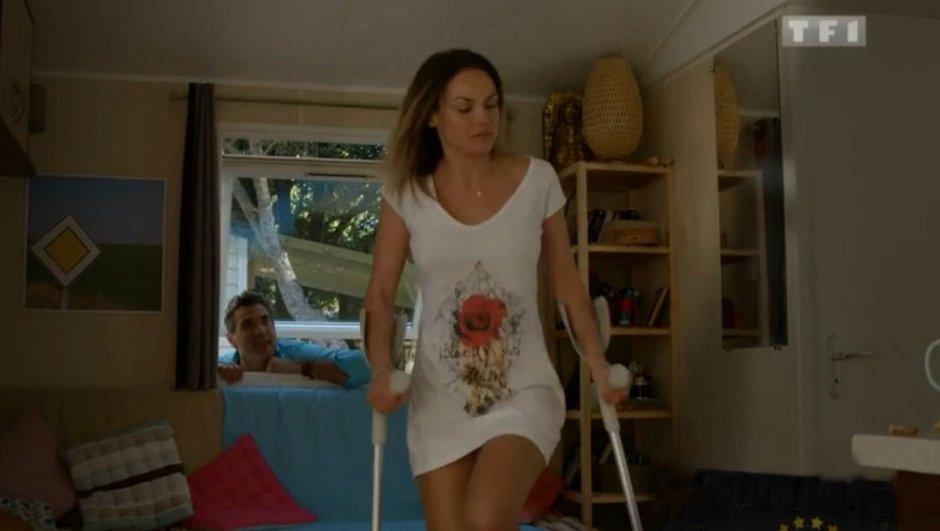 Une femme avec une prothèse de jambe se tient debout sur des béquilles dans un mobil-home.