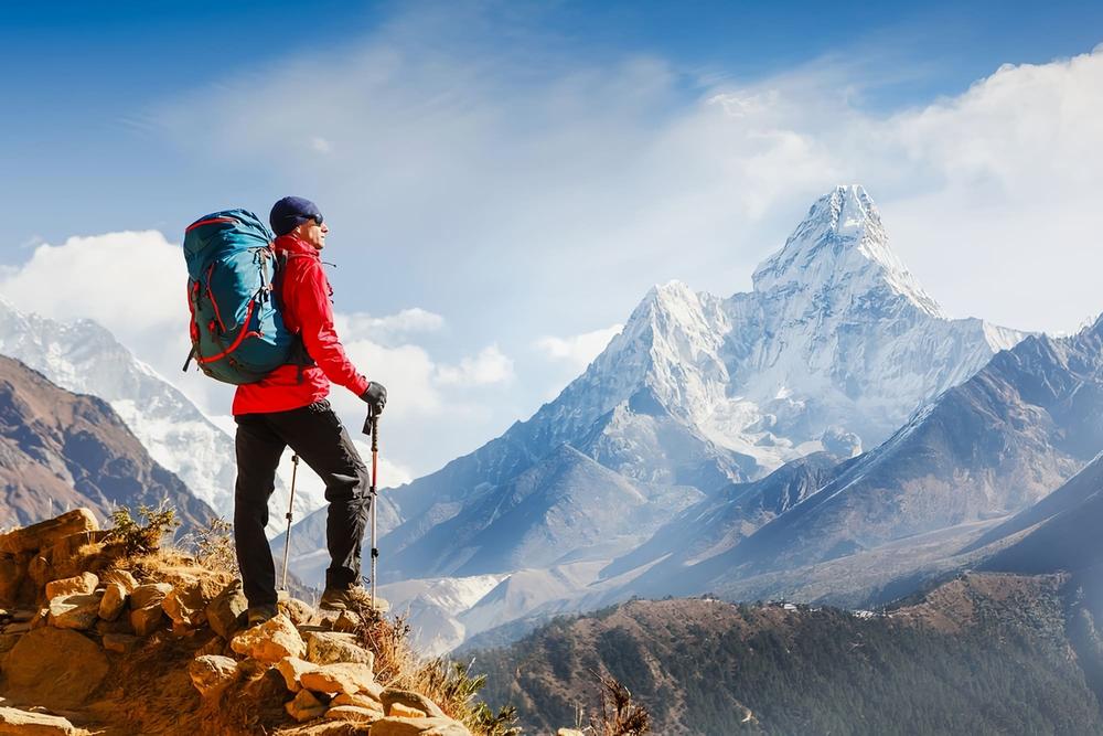 Un homme en équipement de randonnée regarde un sommet enneigé.