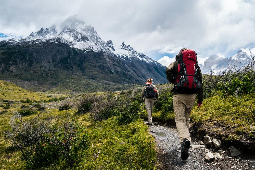 Deux randonneurs marchent sur un sentier de montagne.
