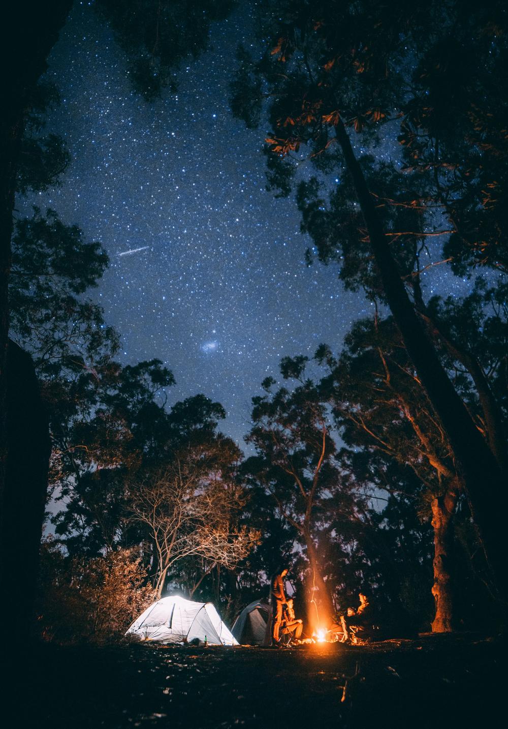 Une tente éclairée la nuit sous un ciel étoilée.