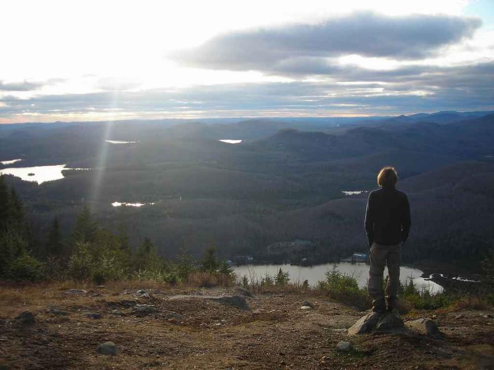 Un homme se tient sur un rocher et regarde le paysage montagneux.