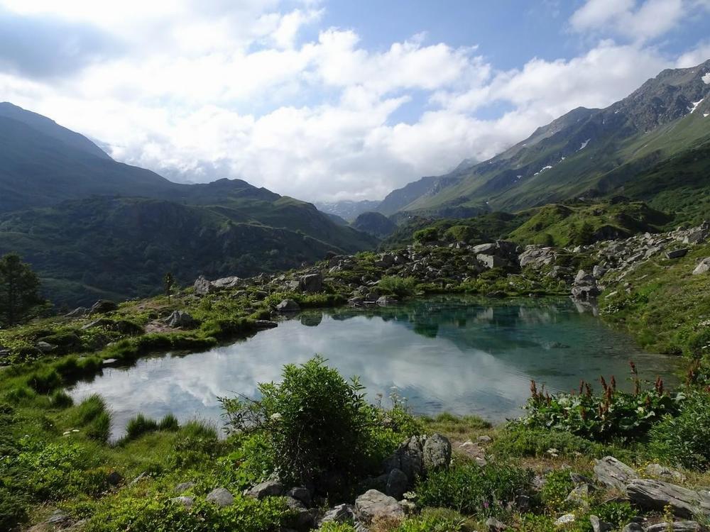 Un lac alpin entouré de montagnes et de verdure.