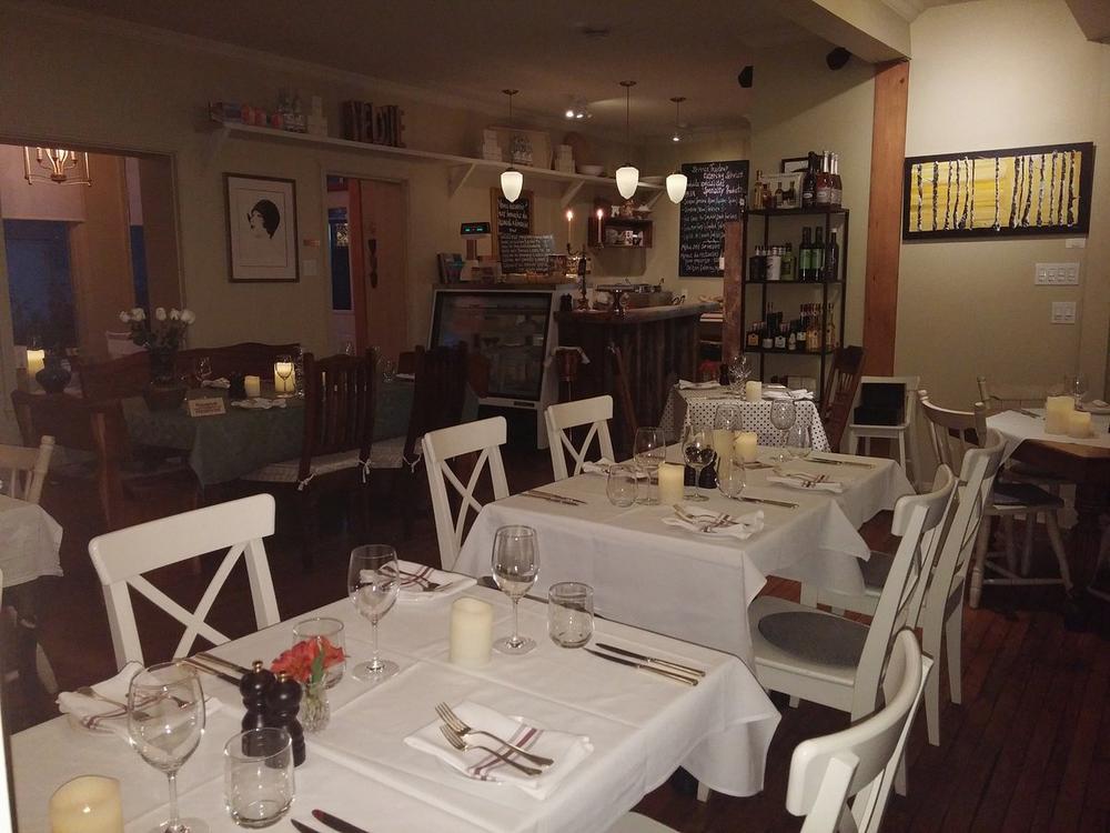 Une salle à manger avec des tables, des chaises et des verres à vin.