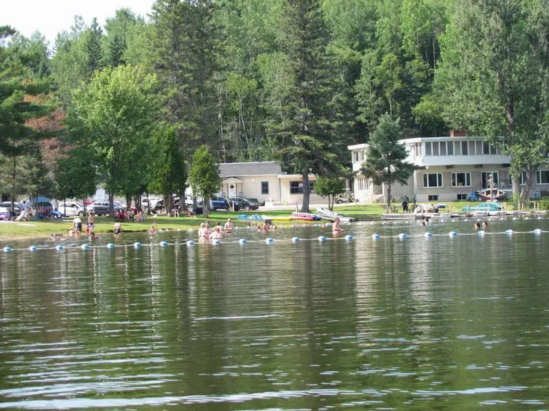 Une vue dun lac avec des gens qui nagent et une maison en arrière-plan.