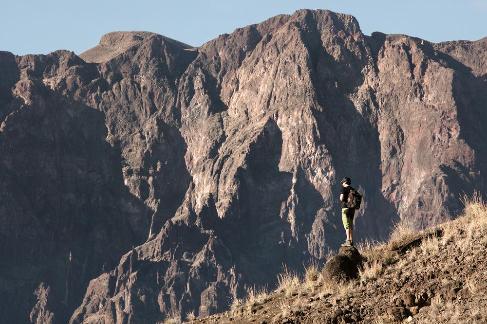 Une personne est debout sur un rocher et regarde un paysage montagneux.