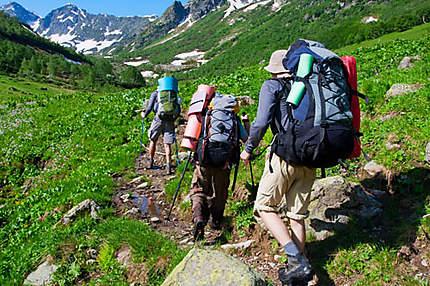 Trois randonneurs marchent sur un sentier de montagne.