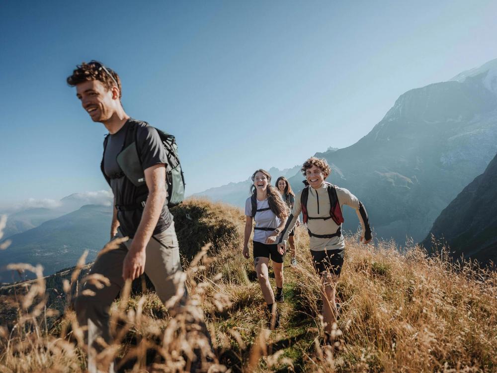 Quatre randonneurs heureux marchent sur un sentier de montagne.
