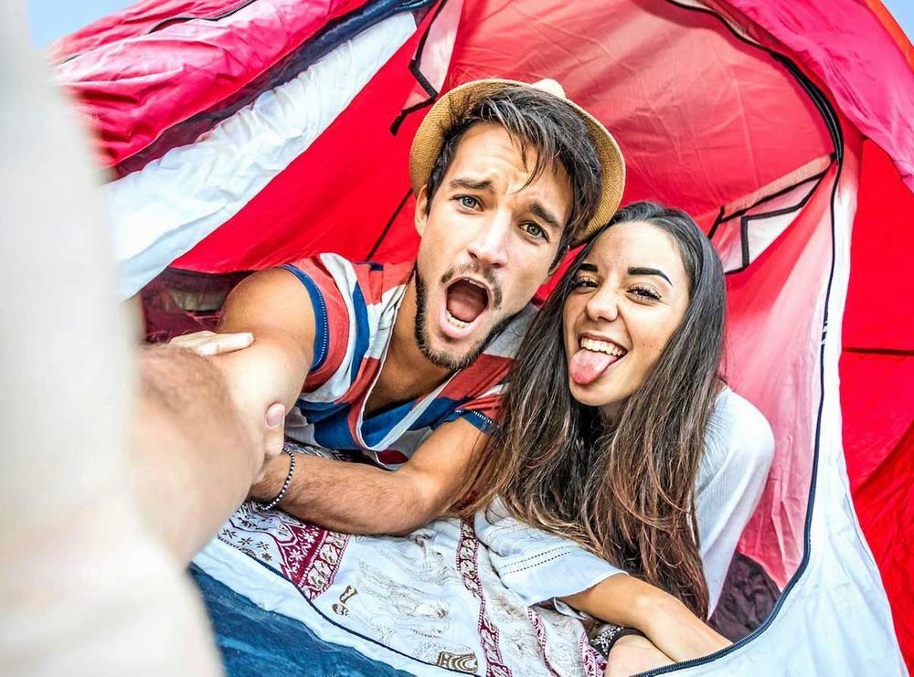 Un jeune couple prend un selfie dans une tente.