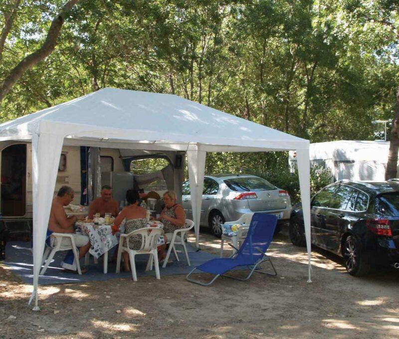 Une famille est en train de manger sous une tente de camping.