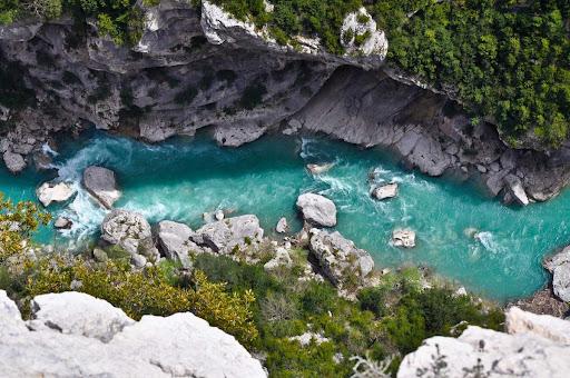 Une rivière turquoise coule dans une gorge rocheuse.