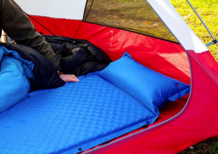 Une personne dort sur un matelas gonflable bleu dans une tente.