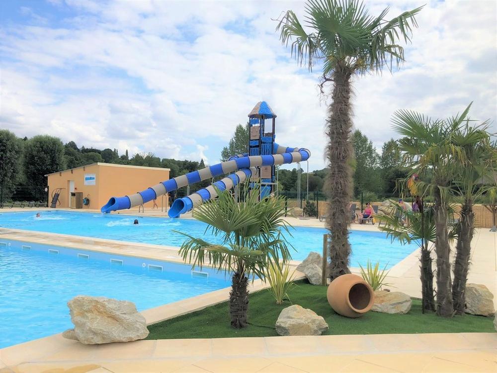 Une piscine avec un toboggan bleu et une aire de jeux aquatiques pour les enfants.