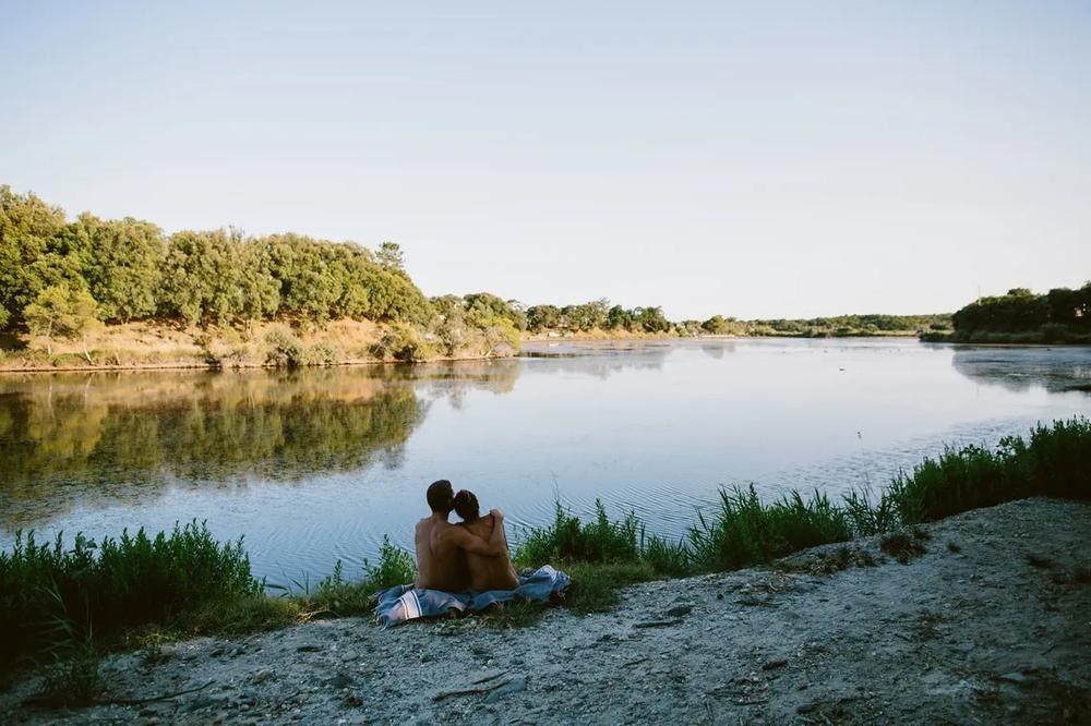 Un couple est assis sur une couverture près dun lac.