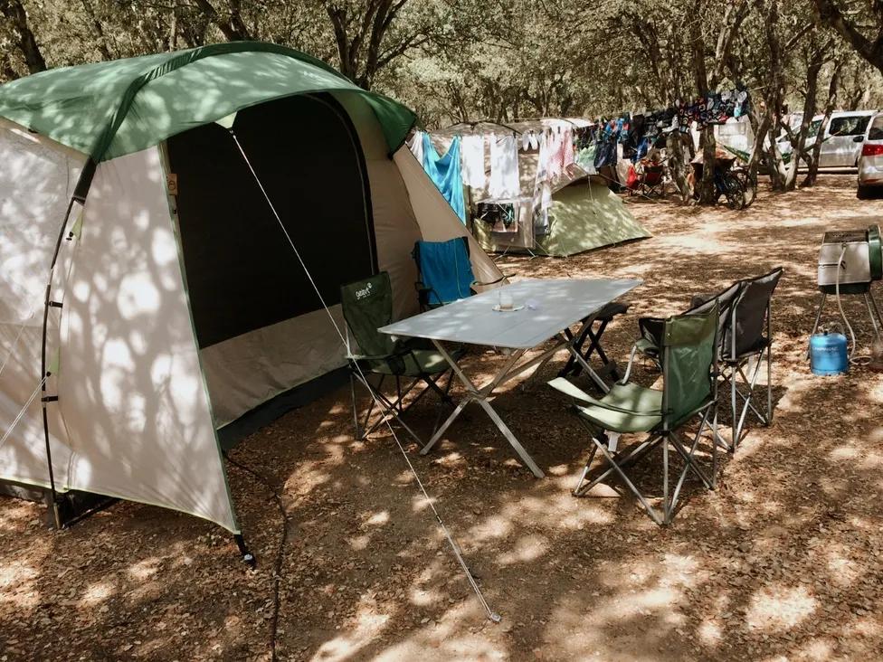 Une tente verte et une table de camping avec des chaises dans un camping.