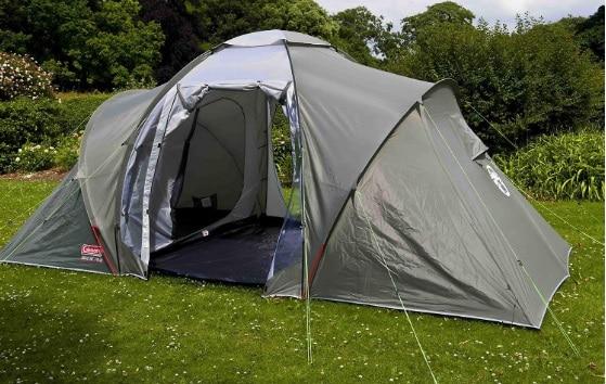 Une tente de camping verte et grise avec quatre pièces et une porte ouverte.