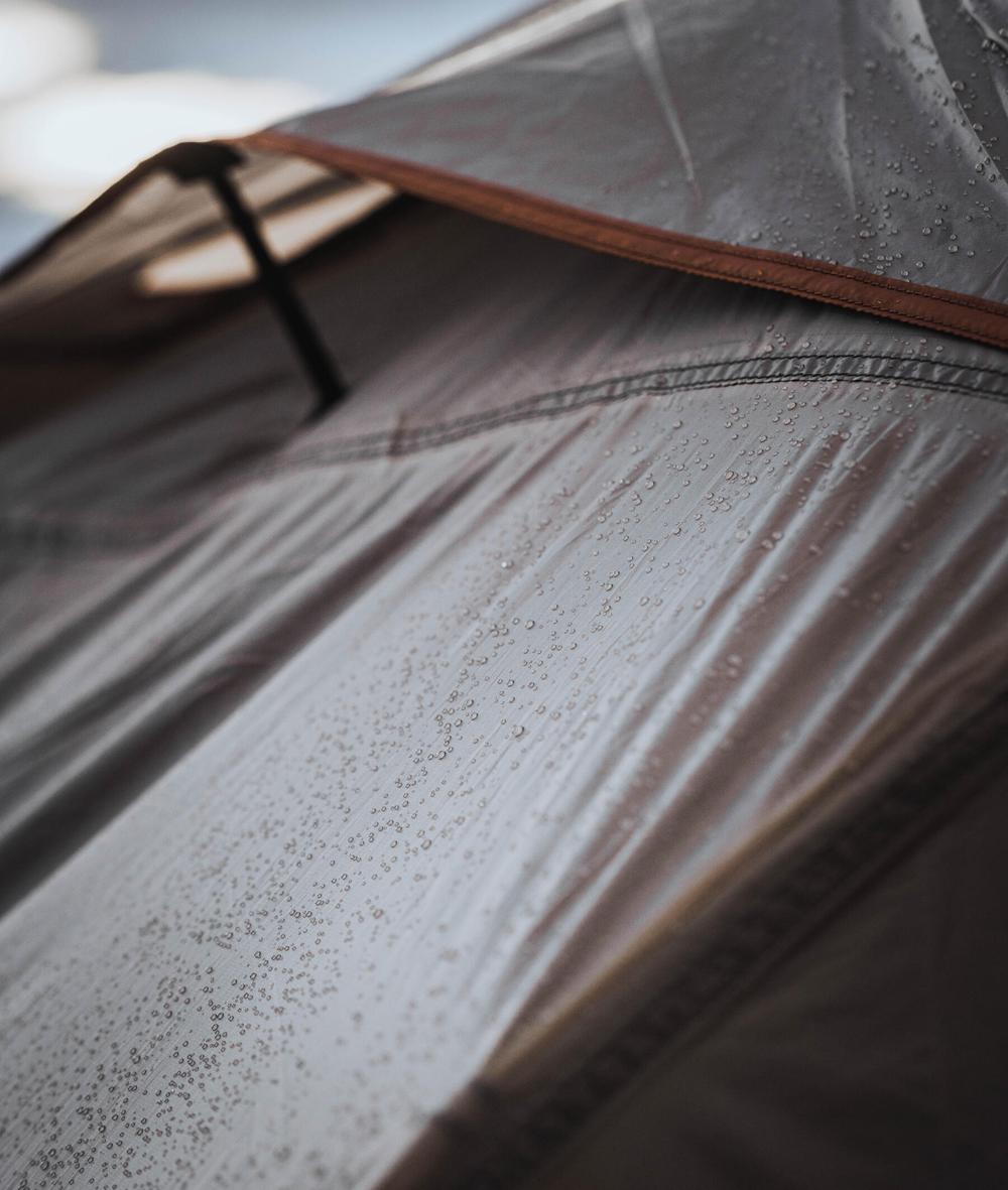 Une image en gros plan dune tente de camping mouillée par la pluie.