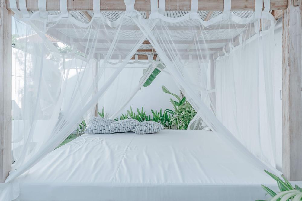 Un lit de repos avec des rideaux blancs transparents.