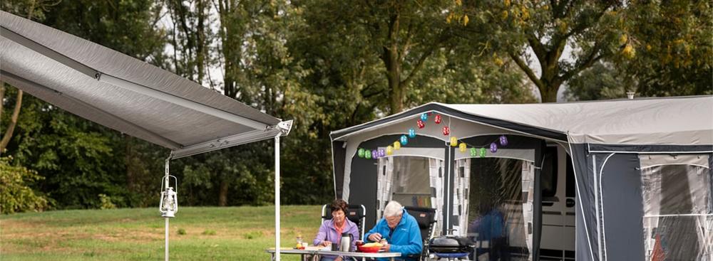 Un couple âgé est assis à une table de camping et mange.